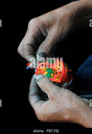 Vecchia donna lavorazione a maglia di un piccolo portafoglio rosso. Il Vietnam, in Asia. Foto Stock