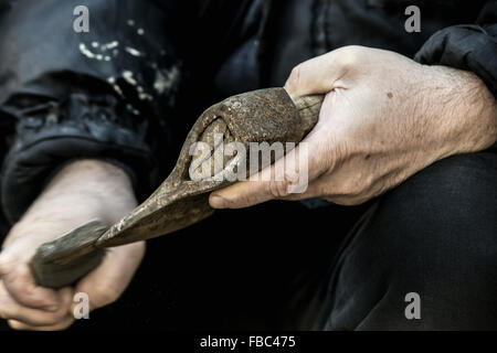 Close-up di mani maschio affilatura di vecchio arrugginito ax con una mola Foto Stock