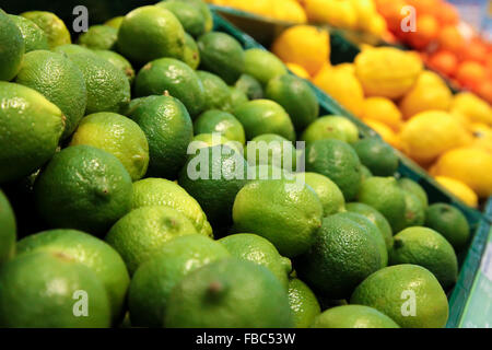 Casse con verde Limette fresche e sfocata limoni giallo su sfondo al mercato Foto Stock