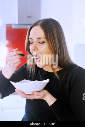 Bella giovane donna 20s mangiare sana prima colazione di porridge Regno Unito Foto Stock