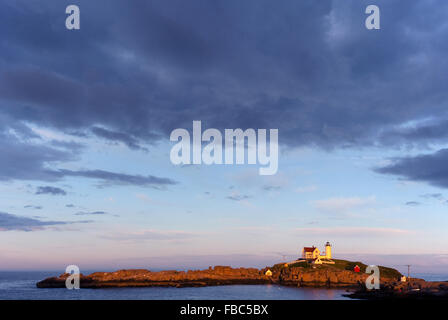 Sun set nella parte anteriore del Nubble (Capo Nededick) faro come nuvole temporalesche approccio su una serata estiva nel Maine. Foto Stock