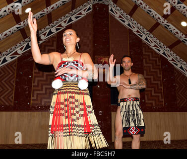 Maori donna che balla con poi(s) mentre l'uomo riecheggia i suoi movimenti, durante un concerto Maori, te Puia, Rotorua, Isola del Nord, Nuova Zelanda Foto Stock