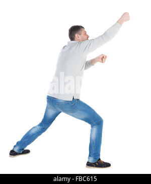 Vista posteriore di uomo in piedi tirando una corda dalla sommità o aggrapparsi a qualcosa. guy guardando. Vista posteriore di raccolta persone. vista posteriore di persona. Isolato su sfondo bianco che poggia il piede guy tira qualcosa da sopra Foto Stock