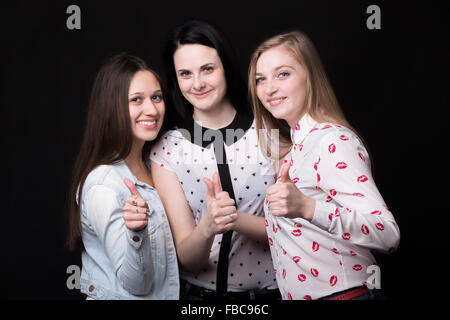 Foto di gruppo dei tre belle ragazze sorridenti insieme mostra pollice in alto Foto Stock