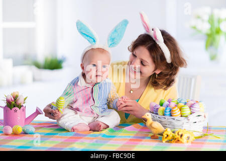 La madre e il bambino di pittura delle uova colorate. Mamma e Bambino con orecchie di coniglietto vernice e decorare uovo di Pasqua. Genitore e bambino giocare in ambienti interni Foto Stock