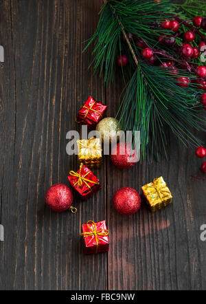 Festive rosso e Golden Regali di Natale e le sfere con abete decorazione su sfondo di legno Foto Stock