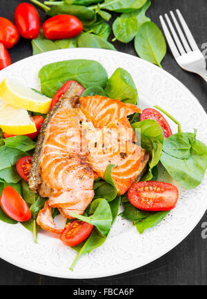 Speziato alla griglia Salmone con spinaci e insalata di pomodori e le fette di limone Foto Stock