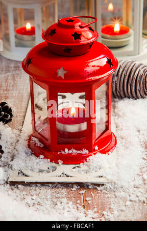 Vintage rosso Natale lanterna con candela che brucia e coni sulla tavola di legno Foto Stock