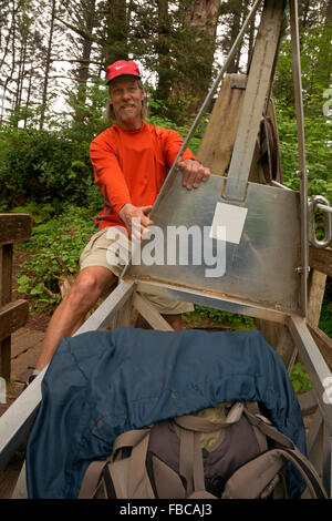 BRITISH COLUMBIA - West Coast Trail escursionista tira un cavo auto per un giro attraverso il Fiume Klanawa in Pacific Rim National Park. Foto Stock