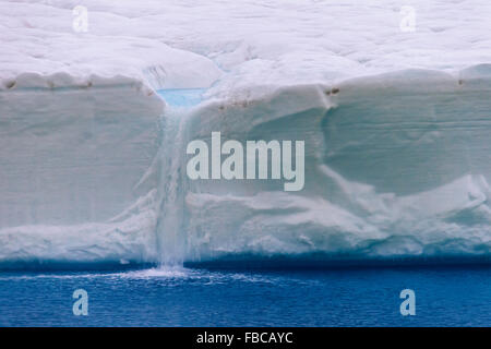 Acqua di disgelo che fluisce dalla parete di ghiaccio di fusione ghiacciaio Brasvellbreen nell'Oceano Artico, Austfonna, Nordaustlandet, Svalbard Foto Stock