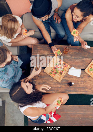 Vista dall'alto del gruppo di giovani aventi le bevande e pizza a parte. Multirazziale amici appendere fuori insieme. Foto Stock