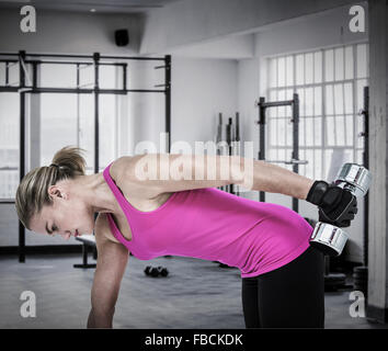 Immagine composita della donna muscolare esercizio con manubri Foto Stock