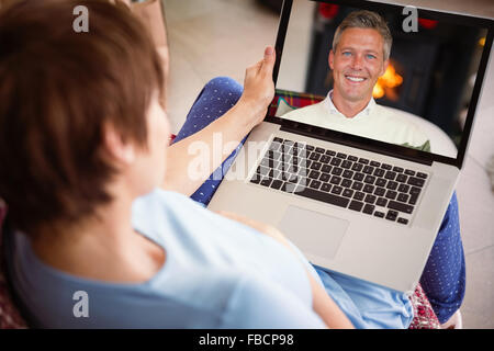 Immagine composita della donna incinta usando il suo computer portatile Foto Stock