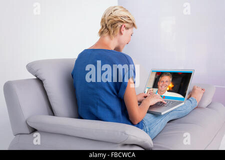 Immagine composita della donna bionda usando il suo computer portatile sul lettino Foto Stock