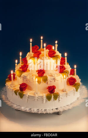 Torta di nozze con rose di marzapane e candele accese Foto Stock