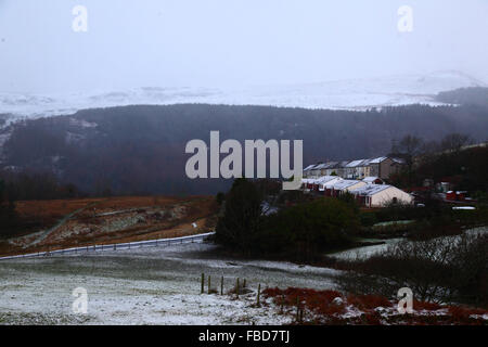 Nant y Moel, Mid Glamorgan, Galles del Sud. 15th gennaio 2016: Vista attraverso il villaggio di Nant y Moel nella valle alta di Ogmore nel Galles del Sud, con nevicate fresche sulle colline Mynydd Llangeinwyr alle spalle. Diversi cm di neve cadde sulle colline durante la notte, chiedendo all'Ufficio MET di emettere un livello giallo grave allarme meteo di neve e ghiaccio per la regione. La strada nell'immagine è la A4061 a Treorchy / Treorci. Credit: James Brunker / Alamy Live News Foto Stock