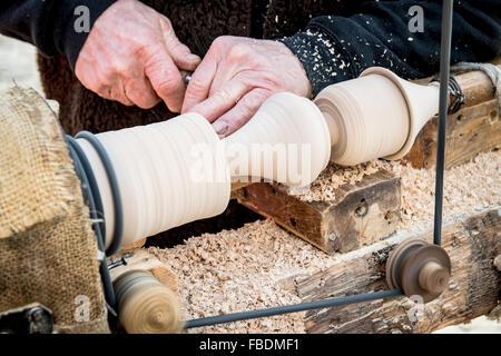 Un artigiano si ritaglia un pezzo di legno utilizzando un vecchio manuale tornio. Foto Stock