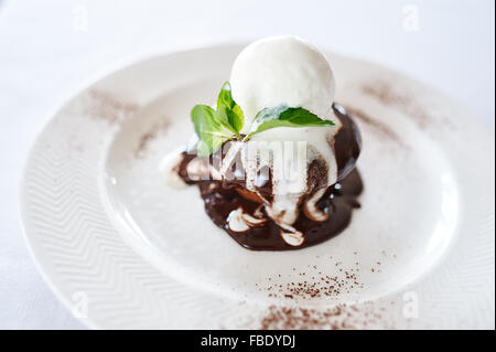 Torta al cioccolato con gelato alla vaniglia sulla piastra bianca Foto Stock