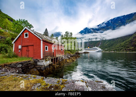 Norvegia paesaggio, la casa sulla riva del fiordo in background attraccare la nave di crociera. Foto Stock