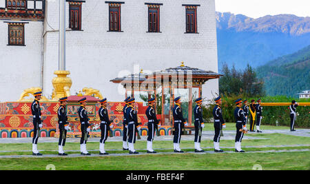 Il cerimoniale di abbassamento di bandiera al tramonto a Tashichho Dzong, sede del potere di governo bhutanese durante il crepuscolo, spazio di copia Foto Stock