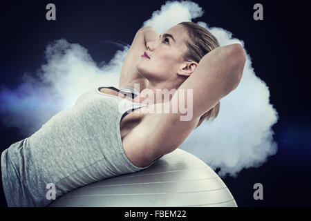 Immagine composita della donna muscolare facendo sit ups sulla palla ginnica Foto Stock