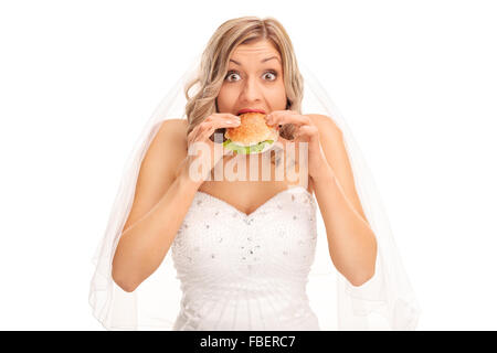 Sorpreso bionda sposa di mangiare un panino e guardando la telecamera isolata su sfondo bianco Foto Stock