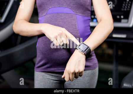 Donna incinta con smart watch Foto Stock