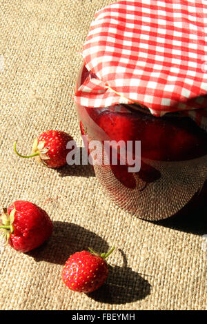 Vaso con confettura di fragole e bacche sul saccheggio sfondo Foto Stock
