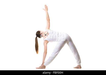 Bellissimo modello fitness le pratiche yoga o pilates, in piedi nel triangolo Yoga asana Trikonasana, stretching esercizio, vista posteriore Foto Stock