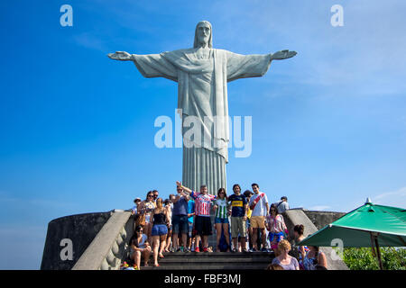 I turisti in posa di fronte del famoso Cristo Redentore statua in cima al monte Corcovado a Rio de Janeiro in Brasile. Foto Stock