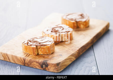 Fette di baguette con cioccolato noccioletta sulla scheda di oliva Foto Stock