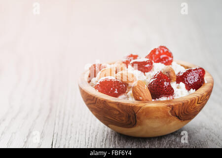 Formaggio con conserva di fragola in ciotola di legno su tavola in legno di quercia Foto Stock