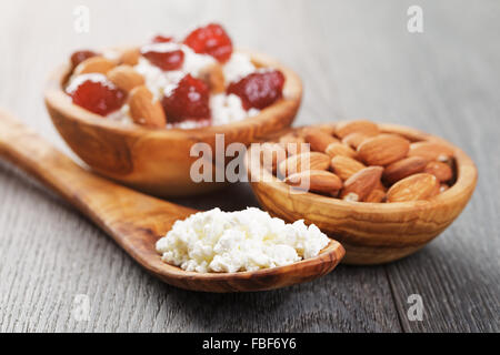 Formaggio con conserva di fragola in ciotola di legno su tavola in legno di quercia Foto Stock