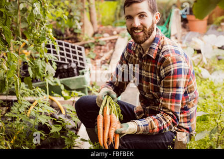 Uomo sorridente tenendo le carote Foto Stock