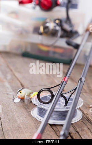 Primo piano gli anelli di guida sulle aste di grafite e cavo watted con blur sullo sfondo dalla pesca affronta e scatole di esca. Foto Stock