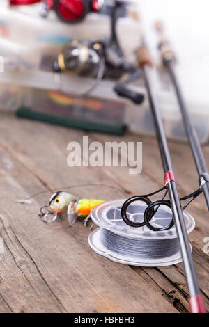 Primo piano gli anelli di guida sulle aste di grafite e cavo watted con blur sullo sfondo dalla pesca affronta e scatole di esca. Foto Stock