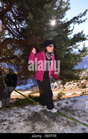 Donna in camicia rosa slacklining nella neve in Queyras, Francia Foto Stock