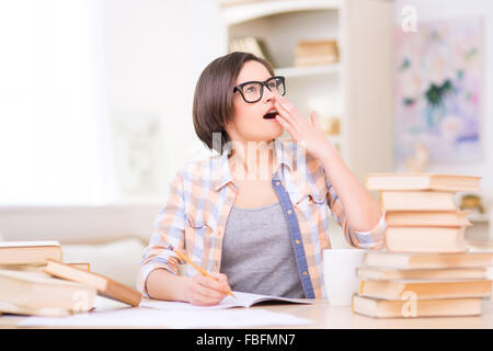 Giovane studente ragazza è sbadigliare durante lo studio a casa. Foto Stock