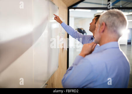 Imprenditore che mostra qualcosa a bordo a un collega Foto Stock