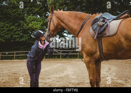 Pilota femmina baciare il suo cavallo Foto Stock
