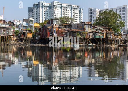 Viste della città baraccopoli dal fiume (in background e nella riflessione dei nuovi edifici) la città di Ho Chi Minh (Saigon), V Foto Stock