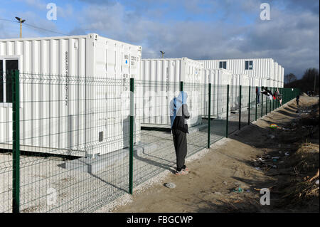 La giungla, Calais, Francia. Venerdì 15 Gennaio 2016. Un rifugiato solitario sorge dal recintato composto del nuovo governo contenitore costruito alloggi per 1000 rifugiati. Foto Stock