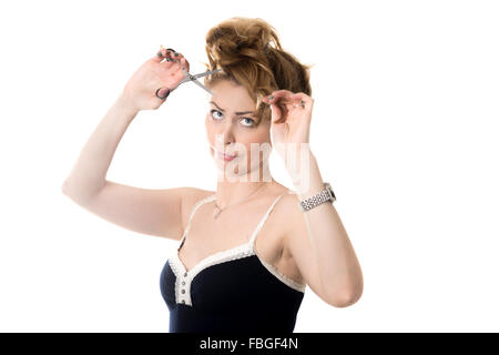 Ritratto di giovane attraente donna bionda con cute funny disordinato e acconciatura infastiditi espressione faccia cercando di tagliare i capelli con Foto Stock