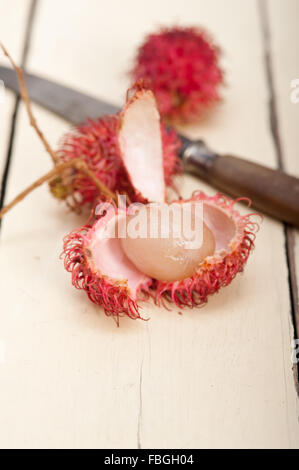 Tropicali freschi frutti di rambutan su tavola in legno rustico Foto Stock