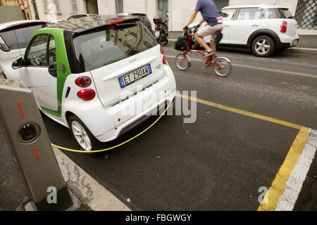 Smart FourTwo auto elettrica essendo caricato da una strada punto di carica, Roma, Italia. Foto Stock