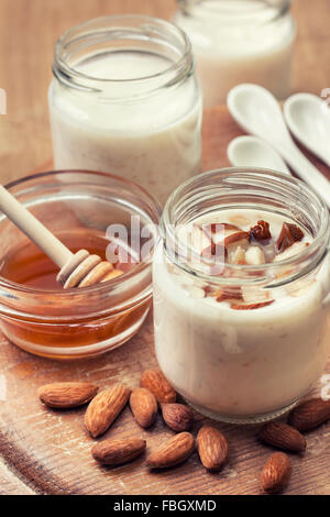 Yogurt fatto in casa latte di mandorla con farina di avena e miele su sfondo di legno (tonificante) Foto Stock