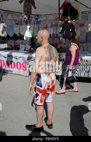 Turisti britannici che riporti il suo tatuato corpo superiore in shorts sono decorati con la Union Jack su un mercato settimanale a Benidorm, Alicante, Foto Stock