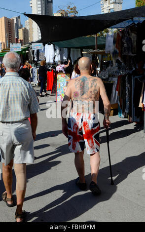 Turisti britannici che riporti il suo tatuato corpo superiore in shorts sono decorati con la Union Jack su un mercato settimanale a Benidorm, Alicante, Foto Stock