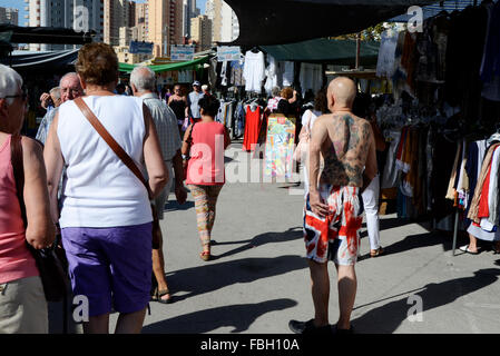 Turisti britannici che riporti il suo tatuato corpo superiore in shorts sono decorati con la Union Jack su un mercato settimanale a Benidorm, Alicante, Foto Stock