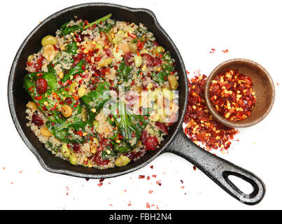 Vista dall'alto di Quinoa spinaci e insalata a base di mirtillo palustre in padella in ghisa con peperoncino rosso tritato. Foto Stock